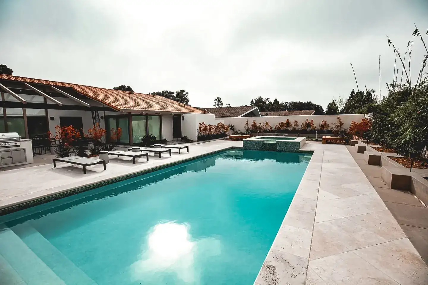 Finished residential pool and pale stone deck with outdoor seating