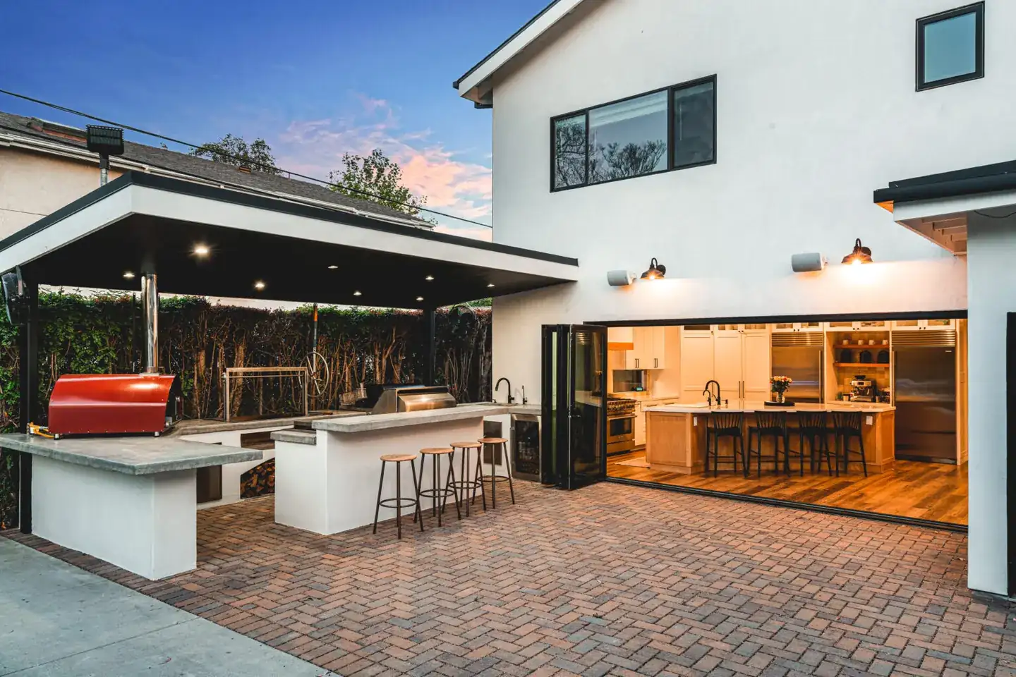 Outdoor kitchen and dining counter illuminated beside a modern home